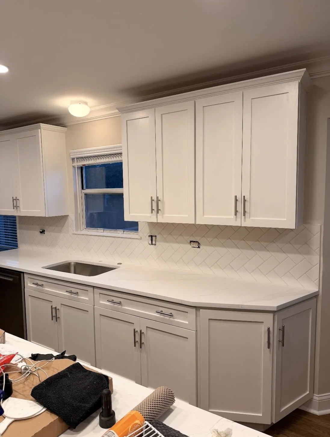 White kitchen backsplash laid in a herringbone pattern
