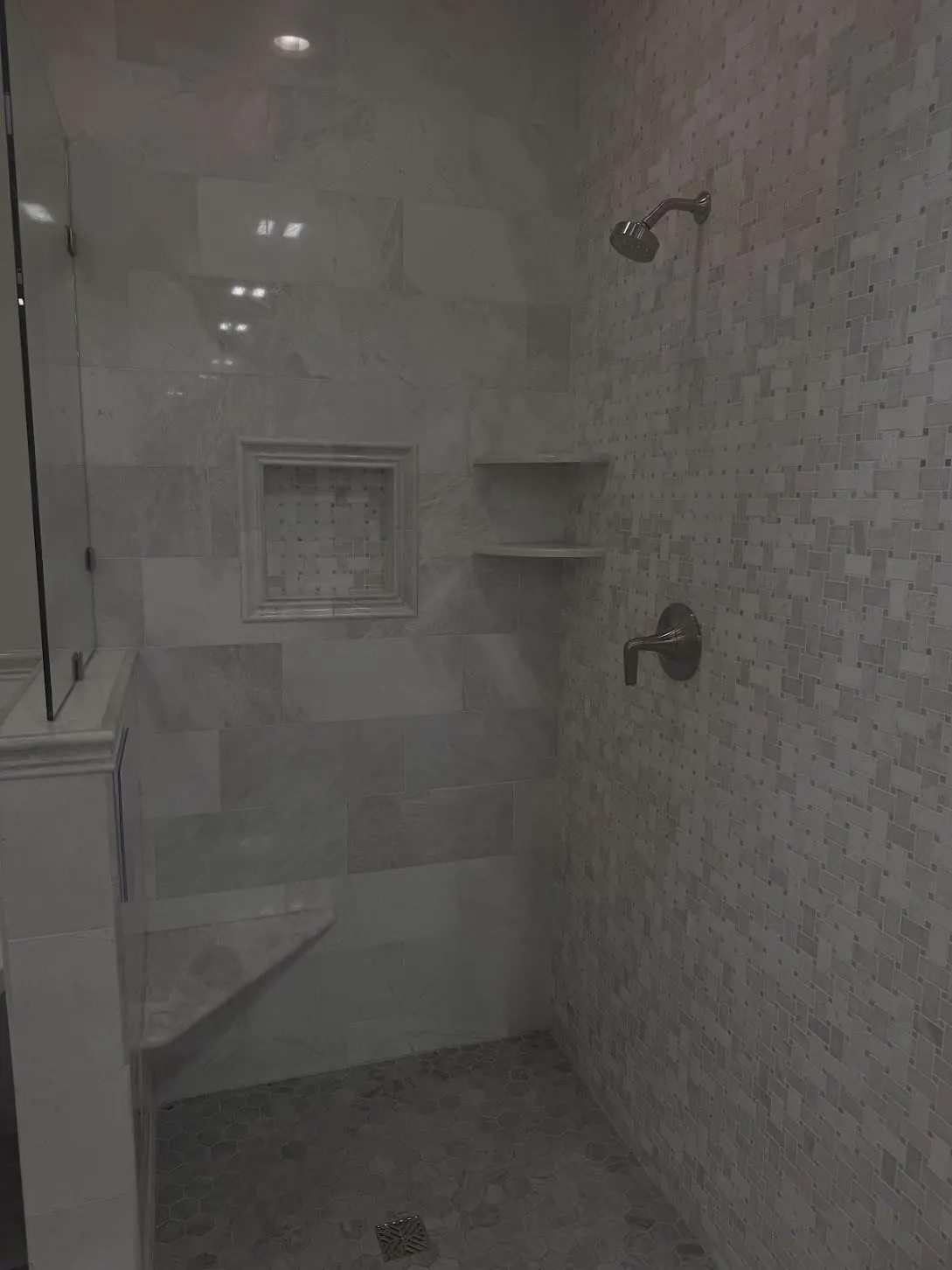 Marble-look tiled shower with a built-in bench